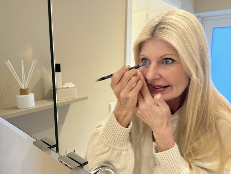 Topage-Model Renate Zott beim Anmalen der Augen mit Kajal vor dem Spiegel