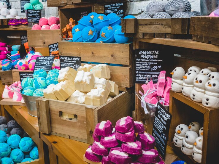 Verschiedene handgemachte Badeprodukte, darunter blaue Kugeln mit Sternen und weiße Schneemannseifen, dekorativ präsentiert.