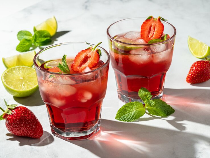 Erdbeer Virgin Mojito Kollagenpulver | © Getty Images/ Natalia Gdovskaia Eiskalte rote Cocktails mit halben Erdbeeren, Limettenstücken und Minzblättern leuchten im Sonnenlicht auf weißem Untergrund. | © Getty Images/ Natalia Gdovskaia