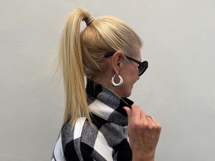Renate Zott Bad Hair Day Sommer Pferdeschwanz Blondhaarige Renate Zott, mittleren Alters mit hochgebundenem Pferdeschwanz und großen silbernen Creolen im Profil.