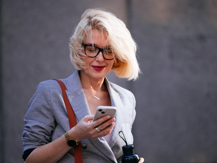 Zu sehen ist eine Frau mittleren Alters mit einem Bob und einer Brille