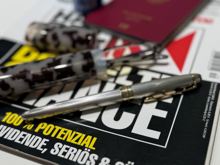 Utensilien für die Flugreise | © Renate Zott Sammlung von Gegenständen, die typischerweise für die Reise vorbereitet werden: ein deutscher Reisepass, ein Magazin, Stifte und eine Lesebrille. | © Renate Zott