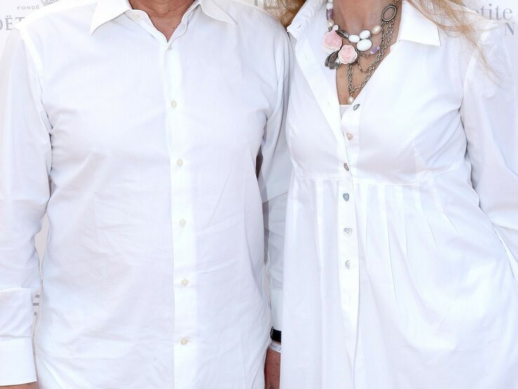 Oberkörper von zwei Personen, die beide weiße Hemden tragen. Die Person auf der linken Seite trägt ein schlichtes weißes Hemd, während die Person auf der rechten Seite ein weißes Hemdkleid mit einer auffälligen Halskette trägt.