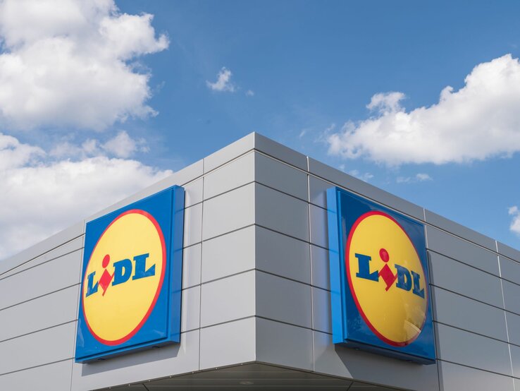 Lidl-Schild vor blauem Hintergrund Moderne Fassade eines Lidl-Supermarkts mit markantem Logo vor blauem Himmel und vereinzelten Wolken.