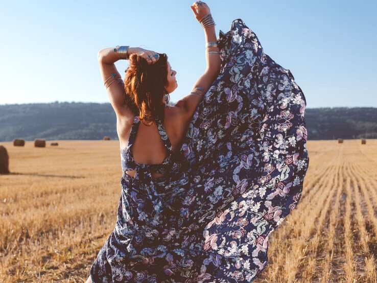 Zu sehen ist eine Frau von hinten, die ein florales, geblümtes Kleid trägt