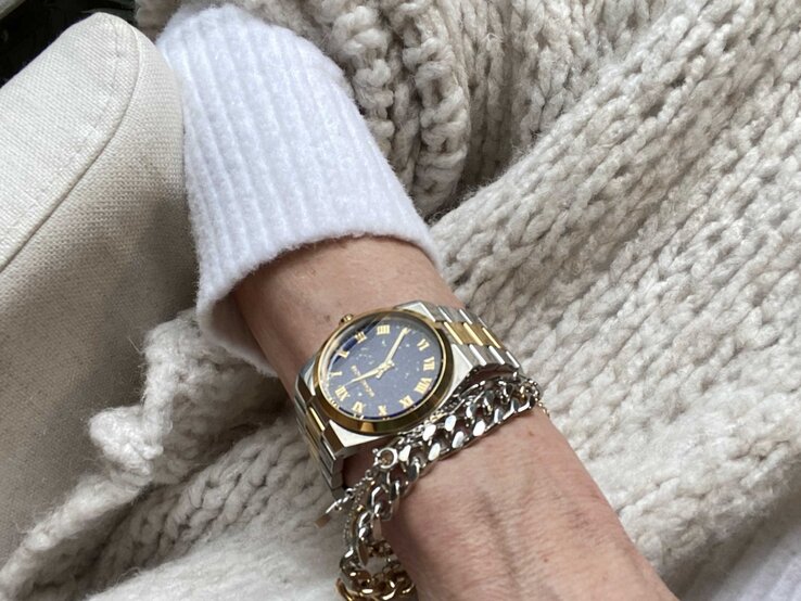Anti-Aging-Accessoires: Handgelenk von Renate Zott mit eleganter Bi-Color-Armbanduhr und silbernem Kettchen ruht auf grob gestrickter, cremefarbener Wolldecke. | © Renate Zott