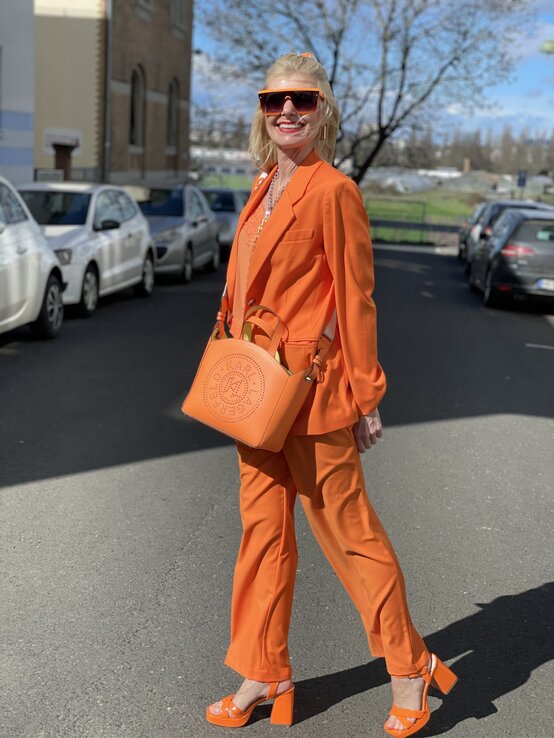 Zu sehen ist Renate Zott, die einen Orangen Zweiteiler trägt | © Renate Zott