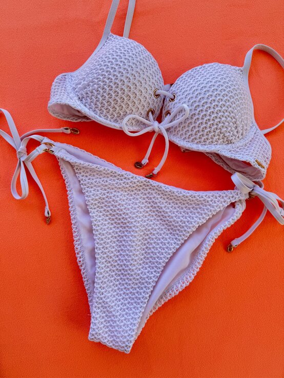 Zu sehen ist ein weißer Bikini mit Kordelzug auf orangen Hintergrund | © Renate Zott