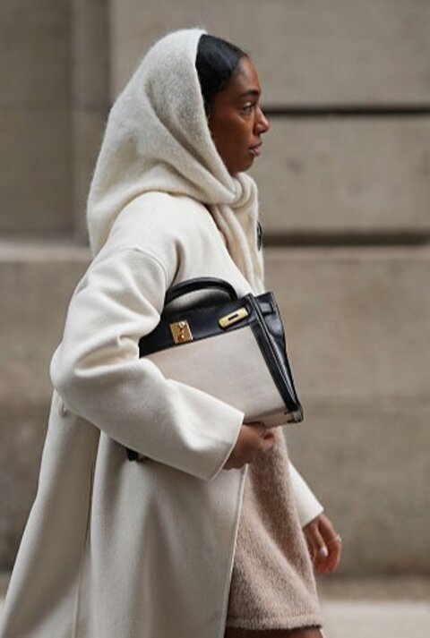 Zu sehen ist eine Frau, die ein beiges Wnteroutfit inklusive Schlupfschal trägt.