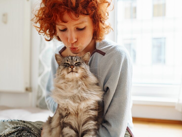 Rothaarige Frau gibt Katze einen Kuss