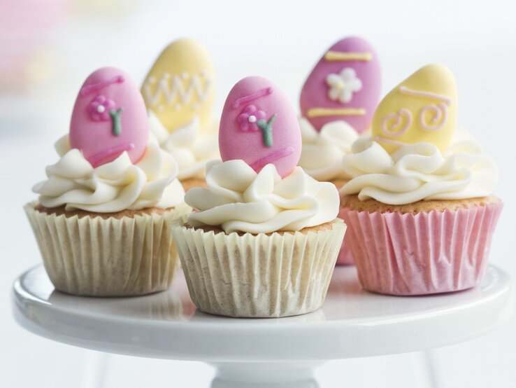 Oster-Cupcakes mit Windbeuteln auf einem weißen Servierteller.