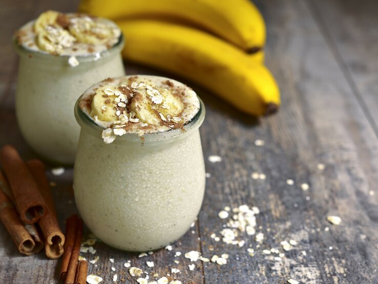 Bananenpudding im Glas – dekoriert mit Haferflocken und Banane auf hölzernem Untergrund.