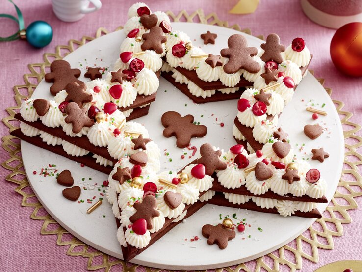 Lebkuchenstern-Torte auf einem weißen Tortenteller auf rosa Hintergrund.