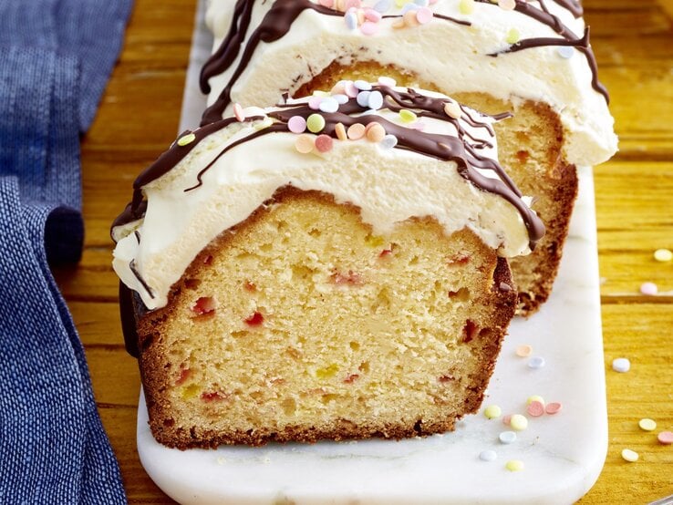 Funfetti-Kuchen mit Schwips auf einem weißen Teller auf hölzernem Hintergrund. 