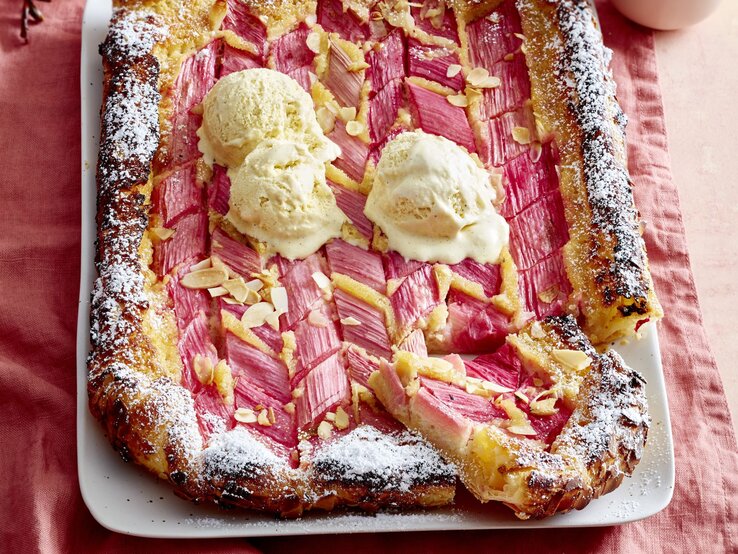 Rhabarber-Mandel-Galette auf einem weißen Teller auf rosa Hintergrund. 