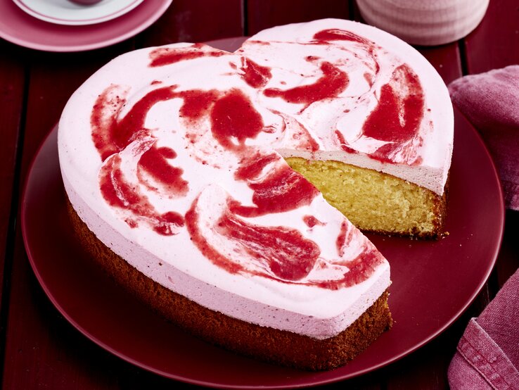 Erdbeer-Herz auf einem roten Teller vor rotem Hintergrund.