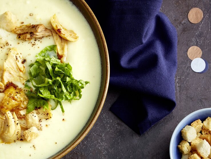 Caesar-Suppe: Vornehmer Genuss, getoppt mit Croûtons Draufsicht: eine Caesar-Suppe auf dunklem Untergrund.
