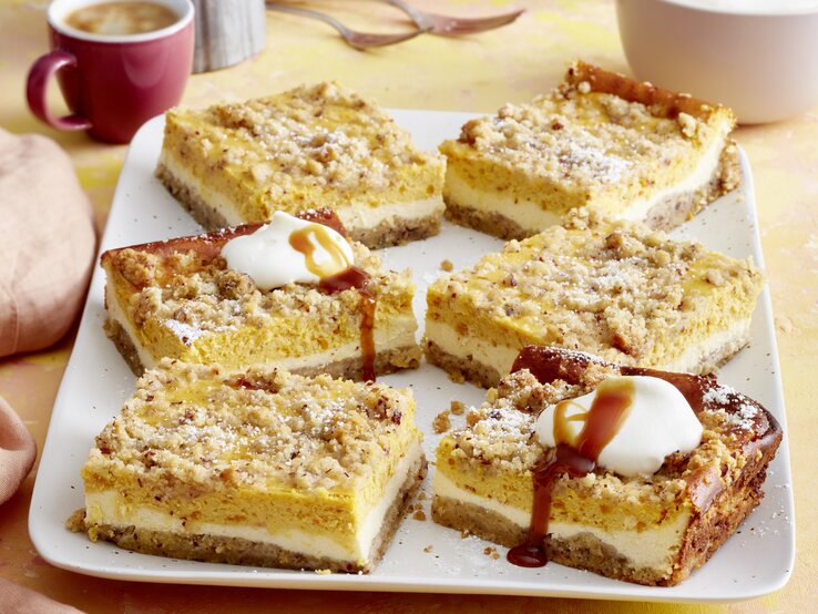 Kürbis-Streuselkuchen Draufsicht auf sieben Stücke des Kürbis-Streuselkuchen auf einer Kaffeetafel.