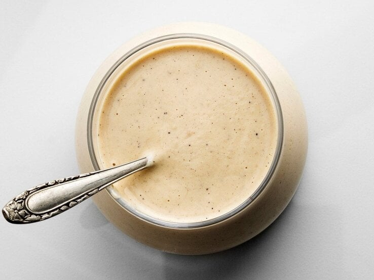 Senfsauce in rundem Glas / Teelöffel aus Silber / Draufsicht