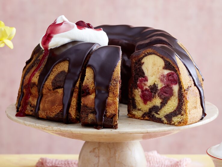 Der Gugelhupf auf einem Tortenständer mit rosa Hintergrund.