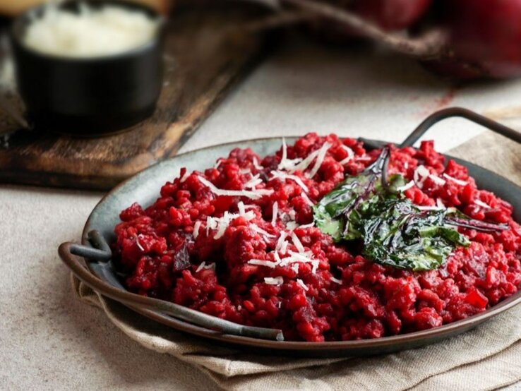 Teller mit vegetarischer One Pot Pasta in Tomaten- und Rote-Bete-Sauce, garniert mit Spinat und Käse.