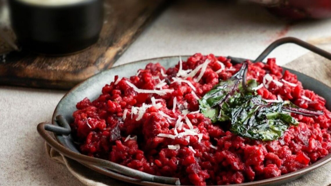 Teller mit vegetarischer One Pot Pasta in Tomaten- und Rote-Bete-Sauce, garniert mit Spinat und Käse.