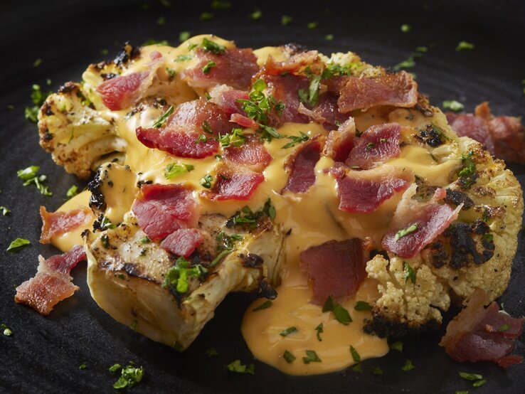 Blumenkohl-Steak mit Käsesoße und Schinken.