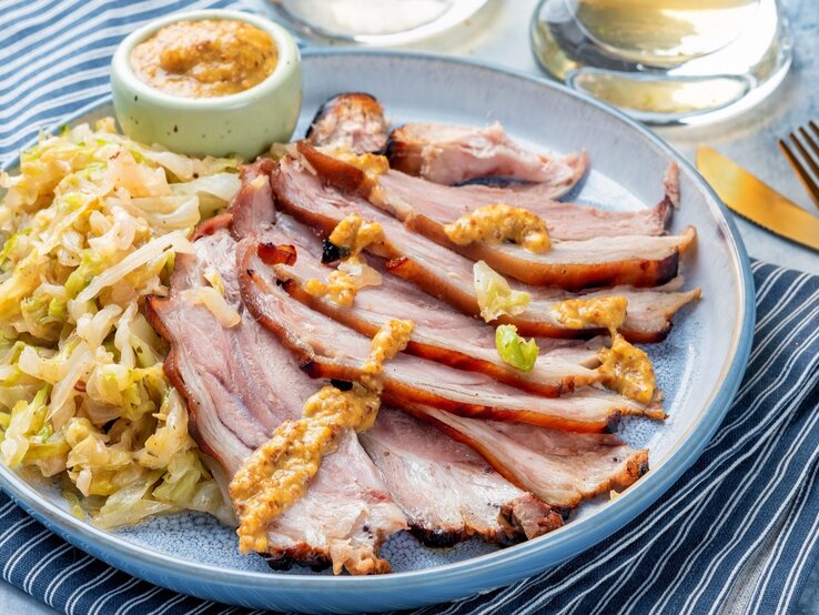 Bayrisch Kraut mit kaltem Braten in Scheiben geschnitten und Senf / Senf / alles auf rundem Teller / Messer und Gabel / Glas Wasser / Untergrund Tuch und Tischplatte