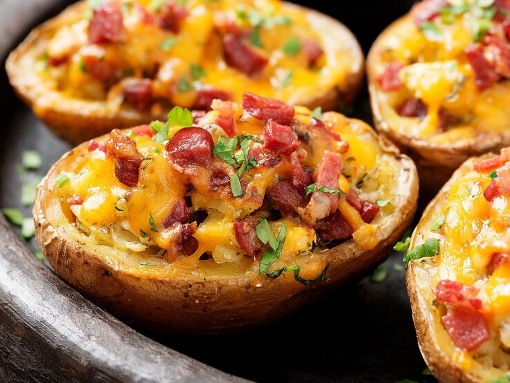 Vier gefüllte Kartoffeln mit Speck und frischen Kräutern / runde Schale / Draufsicht schräg