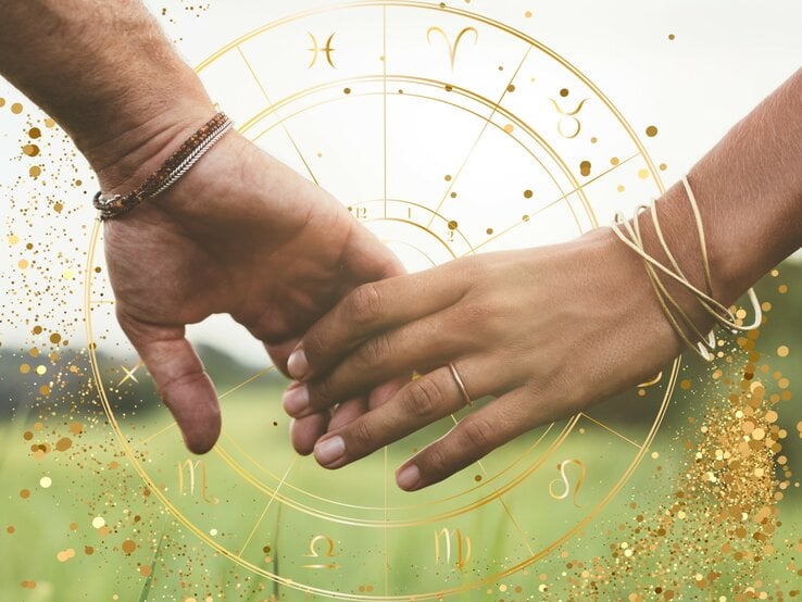 Das Bild zeigt zwei Hände, die sich berühren, vor einem Hintergrund, der an astrologische Symbole und einen Sternzeichenkreis erinnert. Die Hand links gehört einer Person, die ein silbernes und ein kupferfarbenes Armband trägt, während die rechte Hand mehrere goldene Armbänder trägt. Der Hintergrund ist in weichen, grünen Farbtönen gehalten, die an eine Wiese erinnern. Über dem Bild sind goldene Sprenkel und astrologische Symbole verteilt, was dem Bild eine mystische und romantische Atmosphäre verleiht.