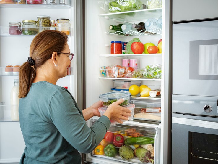 Frau öffnet gefüllten Kühlschrank